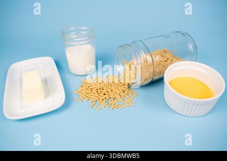 Ingredienti di maccheroni e formaggio confezionati su sfondo blu Foto Stock