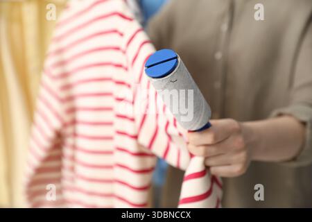 Donna che pulisce la felpa con rullo di lanugine a casa, primo piano Foto Stock