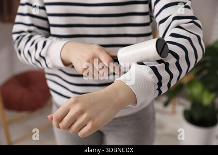 Donna che pulisce la felpa con rullo di lanugine a casa, primo piano Foto Stock