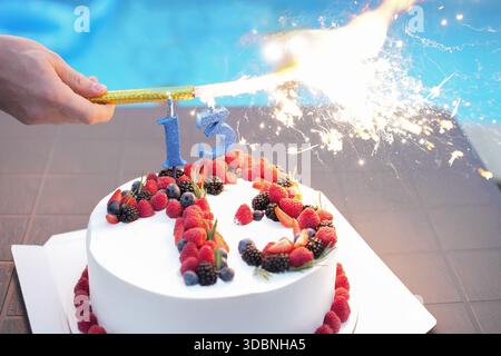 Torta alla panna bianca con frutti di bosco rossi e il numero tredici con fuochi d'artificio Foto Stock