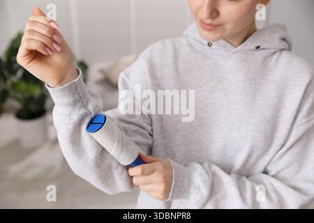 Donna che pulisce la felpa con rullo di lanugine a casa, primo piano Foto Stock