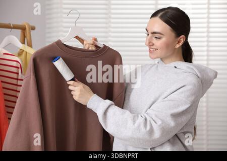 Donna che pulisce la felpa con rullo di lanugine a casa Foto Stock