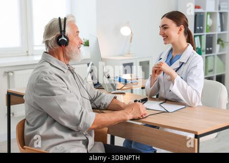 Paziente con cuffie audiometriche sottoposto a test uditivo in clinica Foto Stock
