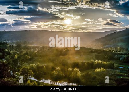 Il tramonto illumina le rovine del castello di Horsburgh, arroccate sopra la Weed Valley, che proiettano raggi caldi sui campi della valle. Foto Stock