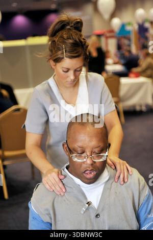 Un massaggiatore che offre massaggi sul posto di lavoro agli impiegati. Foto Stock