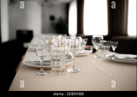 bicchieri da vino vuoti al banchetto serviti al tavolo all'aperto con il sole del tramonto Foto Stock