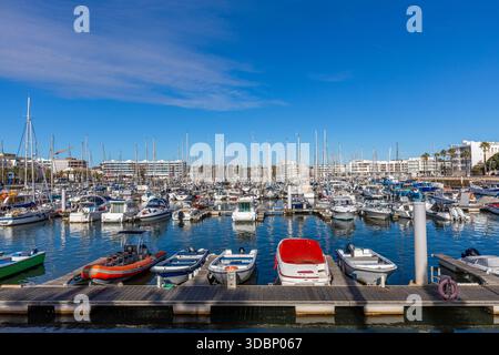 Vista soleggiata del porticciolo di Lagos, Algarve, Portogallo, con numerosi yacht e barche attraccate su acque calme e moderni edifici sul lungomare Foto Stock