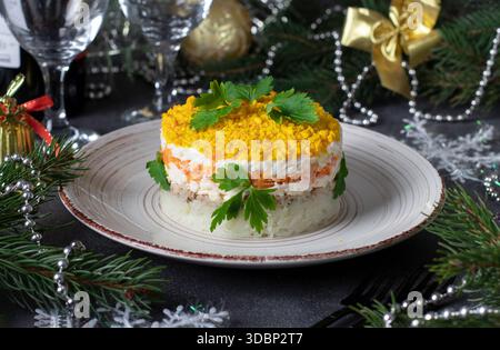 Mimosa insalata di pasta sfoglia con pesce in scatola, patate, formaggio, carote e uova, guarnita con prezzemolo Foto Stock