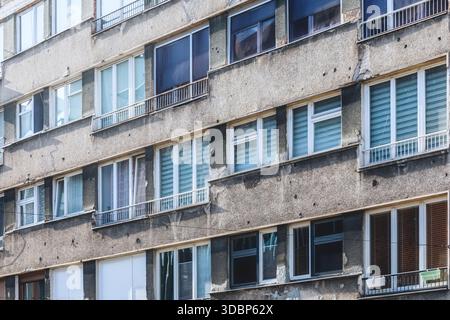 Facciata di un edificio lungo Ulica Zmaja od Bosne (Viale dei cecchini) a Sarajevo, che mostra fori proiettili, danni e contrasto architettonico tra finestre e pareti, Sarajevo, Bosnia ed Erzegovina Foto Stock