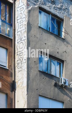 Facciata di un edificio lungo Ulica Zmaja od Bosne (Viale dei cecchini) a Sarajevo, che mostra fori proiettili, danni e contrasto architettonico tra finestre e pareti, Sarajevo, Bosnia ed Erzegovina Foto Stock