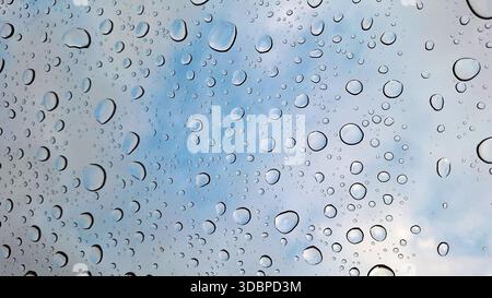 Gocce di pioggia sulla finestra su sfondo blu chiaro del cielo Foto Stock