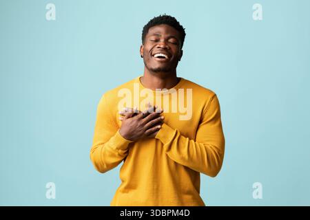 Religioso giovane uomo nero che prega su blu Foto Stock
