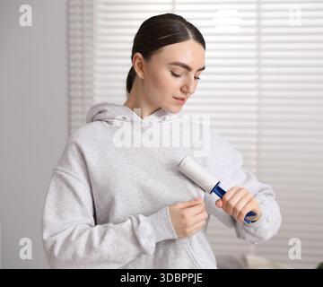 Donna che pulisce la felpa con rullo di lanugine a casa Foto Stock