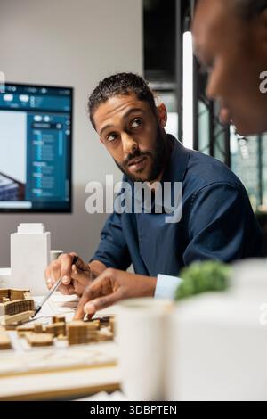 Sviluppatore immobiliare del Medio Oriente che presenta l'idea di un layout residenziale, discutendo con i suoi colleghi del piano generale per l'edilizia abitativa e lo sviluppo urbano. Investimenti immobiliari. Foto Stock