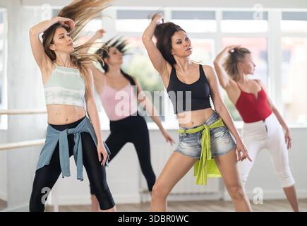 Gruppo di donne moderne che praticano tacchi alti ballano in studio Foto Stock