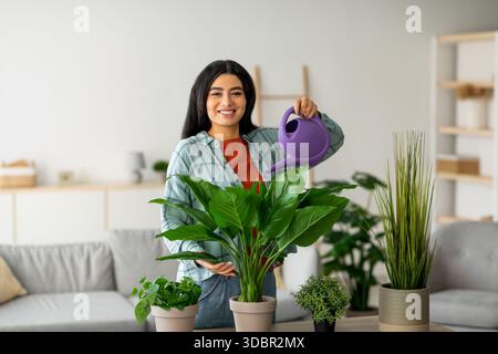 La giovane donna araba si prende cura delle case nell'accogliente soggiorno Foto Stock