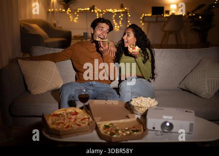 Le coppie si godono la serata con pizza e film insieme nell'accogliente soggiorno Foto Stock