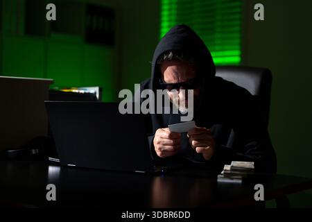 Hacking di criptovalute. Hacking alla ricerca di criptovalute. Hack alla criptovaluta. Hacker in tema di notte buia con cappuccio. Concetto di sicurezza dei dati digitali Foto Stock
