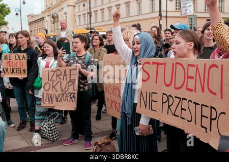 Studenti e attivisti cantano slogan durante una protesta pro-Palestina vicino all'Università di Varsavia, tenendo in mano cartelli e striscioni fatti a mano. Foto Stock