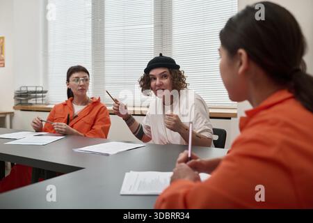 Tre giovani donne adulte sedute a tavola discutono di materiale educativo in aula durante il programma di educazione carceraria Foto Stock