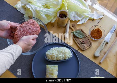 Processo di preparazione di involtini di cavolo ripieni fatti in casa con carne macinata, riso e spezie in un'accogliente cucina casalinga. Tradizionale preparazione di cibi confortevoli Foto Stock