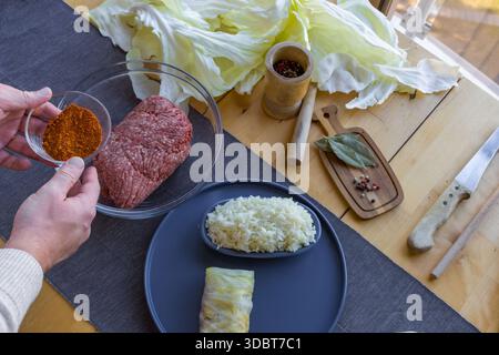 Processo di preparazione di involtini di cavolo ripieni fatti in casa con carne macinata, riso e spezie in un'accogliente cucina casalinga. Tradizionale preparazione di cibi confortevoli Foto Stock