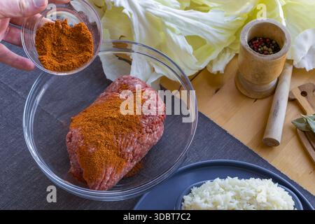 Processo di preparazione di involtini di cavolo ripieni fatti in casa con carne macinata, riso e spezie in un'accogliente cucina casalinga. Tradizionale preparazione di cibi confortevoli Foto Stock