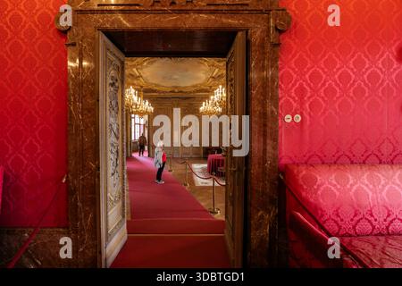 Sigmaringen, Germania - 09 settembre 2025: Veduta degli opulenti interni del castello di Hohenzollernschloss, dove le mura cremisi incontrano con lampadari d'oro, incorniciati Foto Stock
