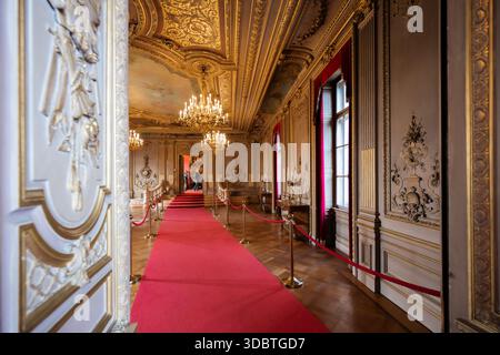 Sigmaringen, Germania - 09 settembre 2025: Vista del corridoio del castello di Hohenzollernschloss con vibrante tappeto rosso, dettagli dorati ornati e luce naturale Foto Stock