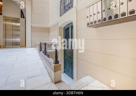 Elegante sala d'ingresso dell'edificio con moderno ascensore e porta d'epoca, Barcellona Foto Stock