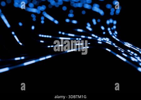 Flussi di dati blu astratti e particelle di luce sfocate che fluiscono dinamicamente su Uno sfondo nero. Concetto di rete veloce, fibra ottica, big data Foto Stock