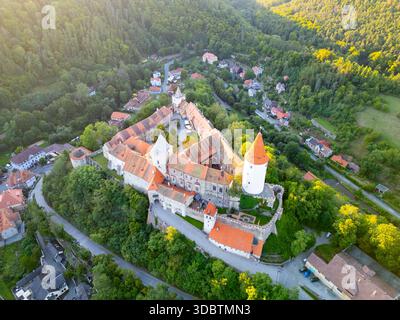 Affacciato sul lussureggiante paesaggio, il Castello di Krivoklat sorge maestosamente nella Boemia centrale. Le calde sfumature del tramonto esaltano il suo fascino medievale, circondato da tranquille colline e pittoreschi villaggi. Foto Stock