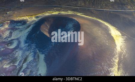 Veduta aerea del cratere vulcanico, circondato da vivaci sfumature gialle e viola, che contrastano nettamente con la terra scura e strutturata, Islanda, Icela Foto Stock