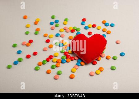 Grande cuore, cuore rosso. Caramelle al cioccolato, piccole e multicolore. Foto Stock