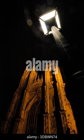 Un lampione solitario, non può competere con la potenza illuminata del fronte occidentale di Beverley Minster in una notte buia, East Yorkshire, Inghilterra. Foto Stock