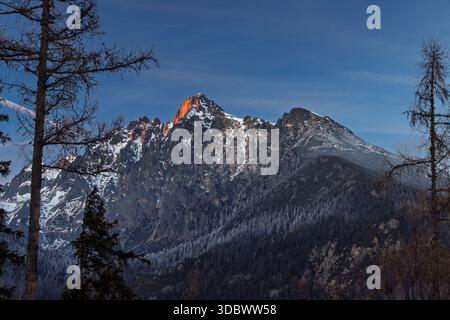 Picco Lomnicky nel Parco Nazionale degli alti Tatra, Slovacchia, Europa. I raggi dorati del sole abbelliscono la vetta della montagna, creando un incredibile spettacolo di luce e. Foto Stock