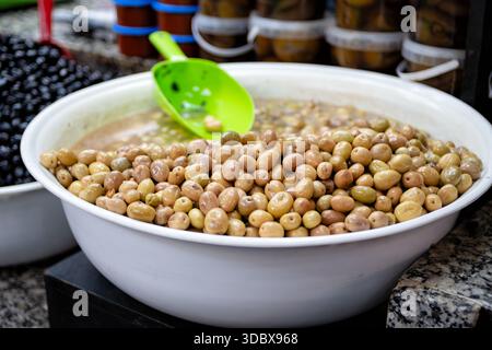 Marrakech. Una grande ciotola di olive marocchine fresche e verdi in vendita in un suk. I clienti possono scegliere e servire da soli Foto Stock