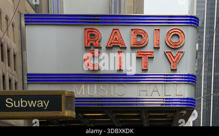La vista del radioso segnale radio City Music Hall si illumina con vivaci lettere rosse sulla facciata dell'edificio, un faro di intrattenimento, New York, New York Foto Stock