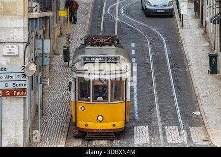 Vista dall'alto del tram giallo 28 che guida su piste curve di ciottoli nel centro storico di Lisbona, Portogallo. Lisbona Portogallo, 23 marzo 2015. Foto Stock