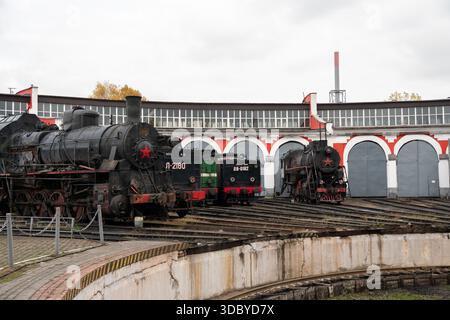 Mosca, Russia - 18 ottobre 2025: Locomotive a vapore dell'epoca sovietica esposte su un giradischi ferroviario presso il museo Povorotny Krug, archi della roundhouse Foto Stock