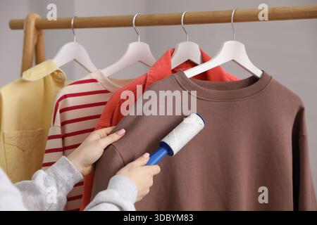Donna che pulisce la felpa con rullo di lanugine a casa, primo piano Foto Stock