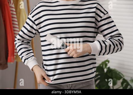 Donna che pulisce la felpa con rullo di lanugine a casa, primo piano Foto Stock