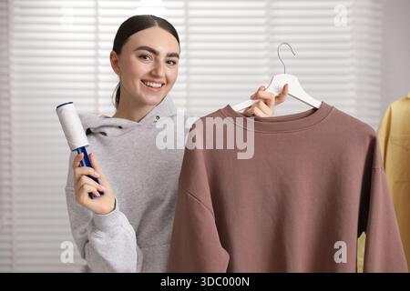 Donna che pulisce la felpa con rullo di lanugine a casa Foto Stock