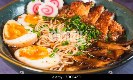Ramen katsu di pollo croccante con uova sode, germogli di bambù e torta di pesce naruto. Brodo ricco e saporito. Cibo giapponese perfetto in una ciotola. Foto Stock