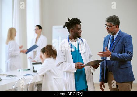 Uomo di mezza età consulenza giovane adulto uomo Nero in Ufficio medico Foto Stock