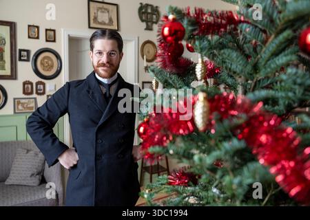 Colonia, Germania. 18 dicembre 2025. Valerio Bonanno, che celebra il Natale come 125 anni fa, si erge accanto al suo albero di Natale. Credito: Thomas Banneyer/dpa/Alamy Live News Foto Stock