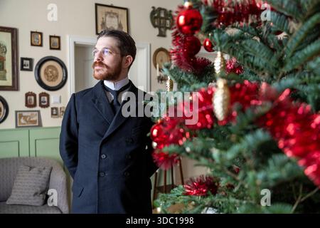 Colonia, Germania. 18 dicembre 2025. Valerio Bonanno, che celebra il Natale come 125 anni fa, si erge accanto al suo albero di Natale. Credito: Thomas Banneyer/dpa/Alamy Live News Foto Stock
