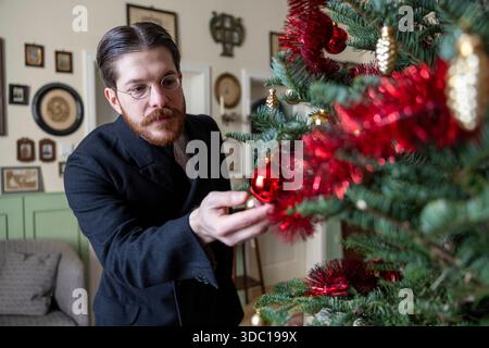 Colonia, Germania. 18 dicembre 2025. Valerio Bonanno, che celebra il Natale come 125 anni fa, guarda un bauble sul suo albero di Natale. Credito: Thomas Banneyer/dpa/Alamy Live News Foto Stock