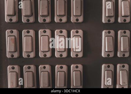Rovigo, italia 18 dicembre 2025: Serie di interruttori vintage di controllo dell'alimentazione su un vecchio pannello a parete, che illustrano i concetti di gestione dell'energia elettrica e di out Foto Stock
