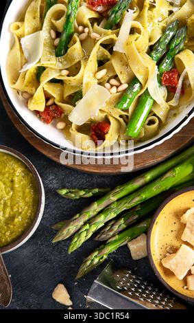 Fituccine con pesto di basilico e pinoli su un piatto bianco. Fituccine al pesto secondo una tradizionale ricetta italiana su un backgroun scuro Foto Stock